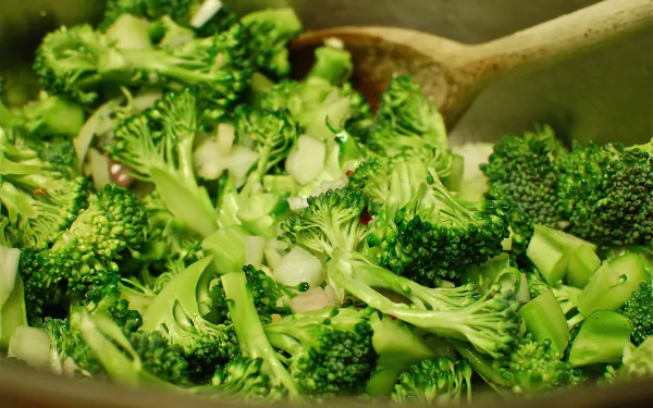 Close-up of vibrant cooked broccoli florets in a pan, food-themed 2K Quad HD PC desktop wallpaper and background.