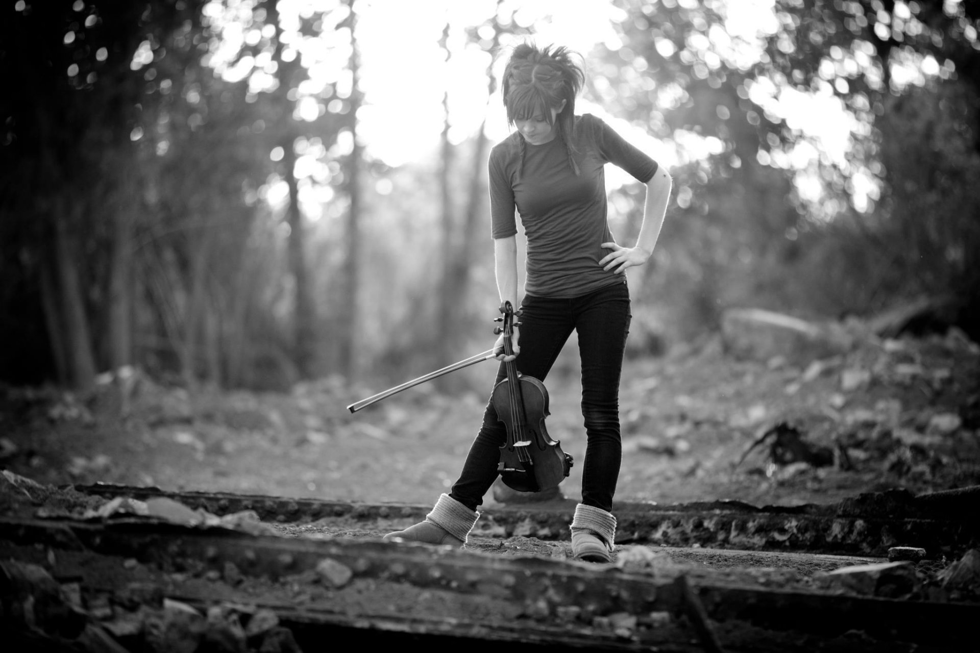 Black-and-white HD PC desktop wallpaper/background: female violinist standing on forest steps with violin and bow, music-themed moody portrait.