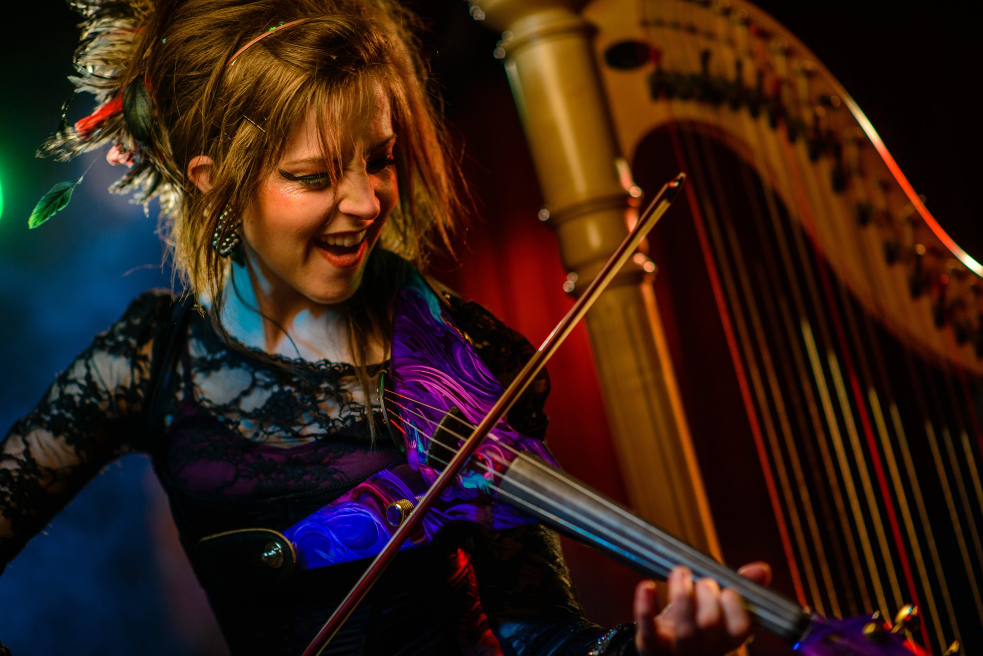 A vibrant 4K Ultra HD desktop wallpaper featuring Lindsey Stirling passionately playing the violin, surrounded by colorful stage lights and musical atmosphere.