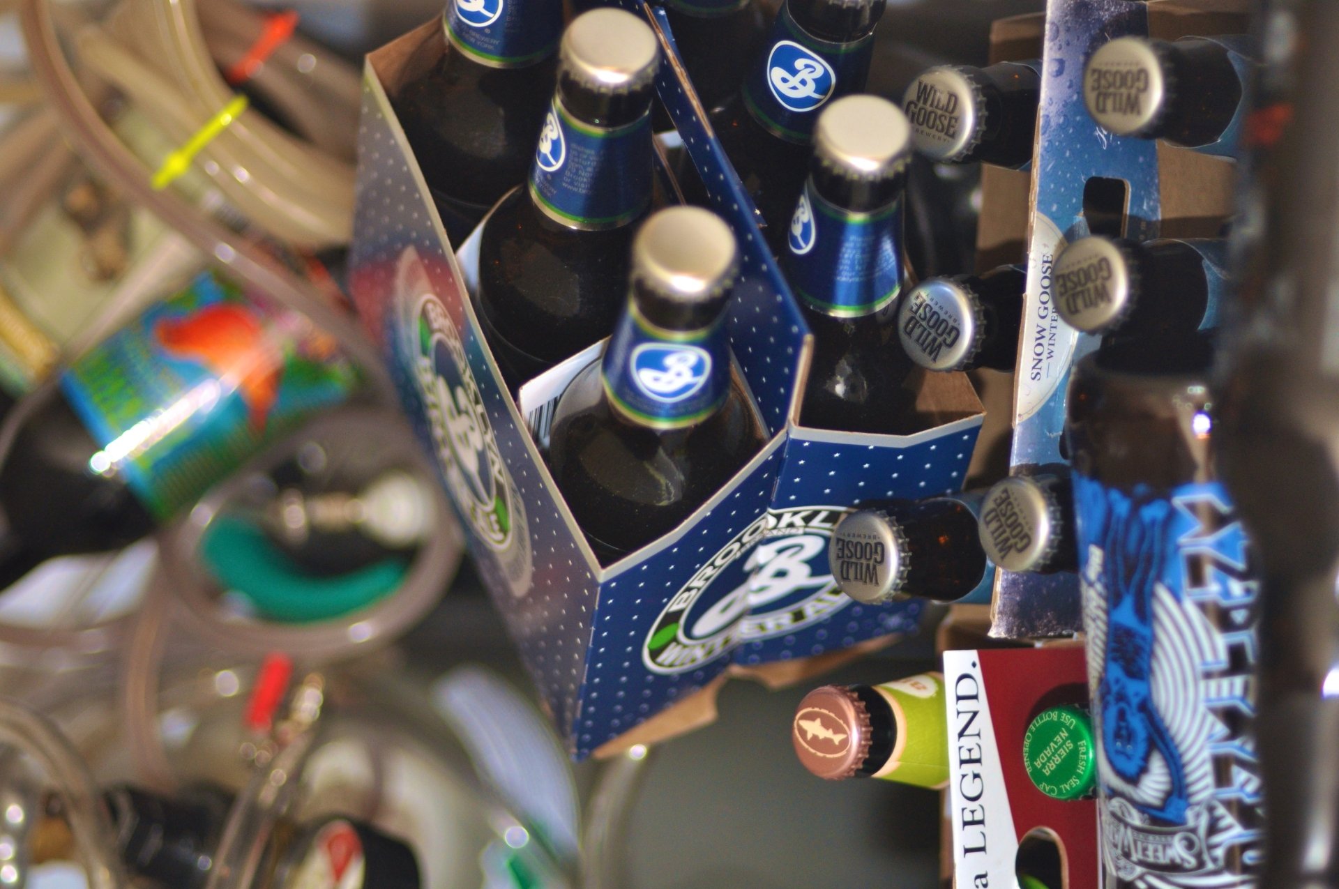 4K Ultra HD wallpaper featuring a close-up of a six-pack of bottled beer surrounded by various food and drink items on a cluttered surface.