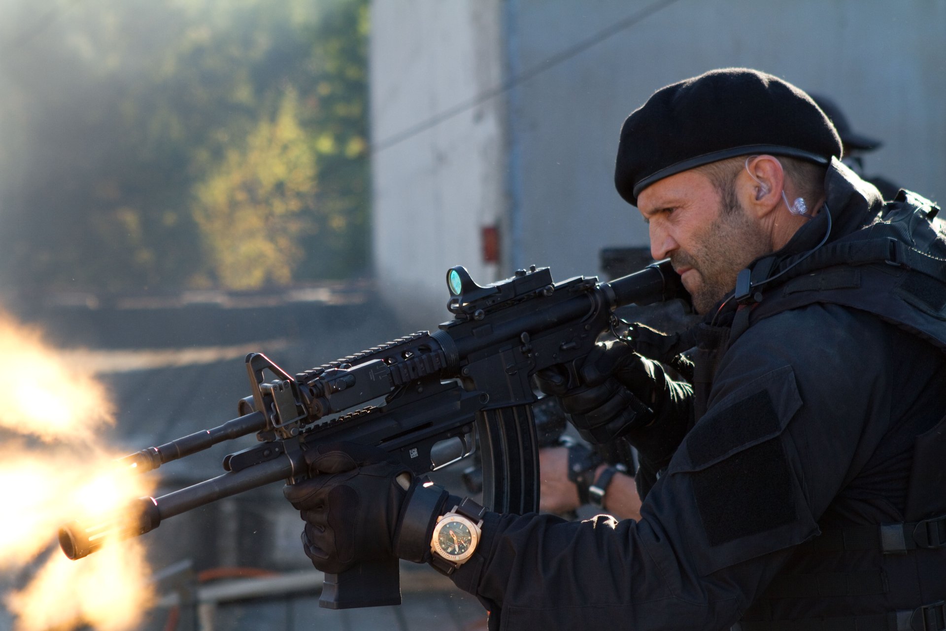 Jason Statham as Lee Christmas in The Expendables 2, firing a machine gun in an intense 4K Ultra HD movie desktop wallpaper.
