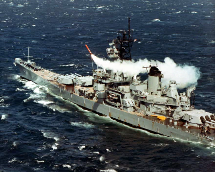 USS New Jersey (BB-62) battleship warship at sea, firing a broadside; military vessel photographed for a 2K Quad HD PC desktop wallpaper.