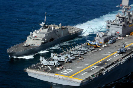 USS Freedom (LCS-1) littoral combat ship alongside an aircraft carrier flight deck with helicopters; USS Cape Gloucester (AKV-9) markings — United States Navy military 4K wallpaper.