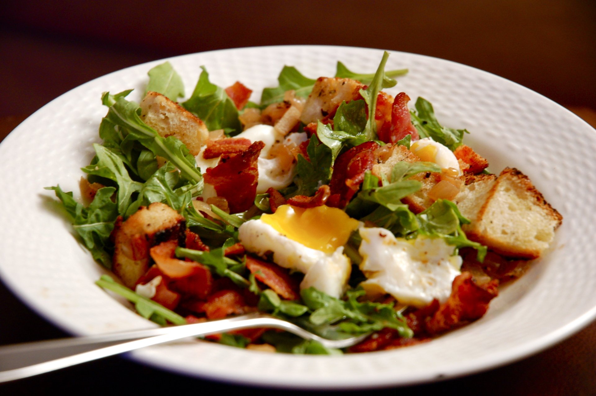 A vibrant plate of Salade Lyonnaise with fresh greens, crispy bacon, croutons, and a perfectly cooked egg, captured as an HD PC desktop wallpaper background.