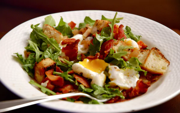 A vibrant plate of Salade Lyonnaise with fresh greens, crispy bacon, croutons, and a perfectly cooked egg, captured as an HD PC desktop wallpaper background.