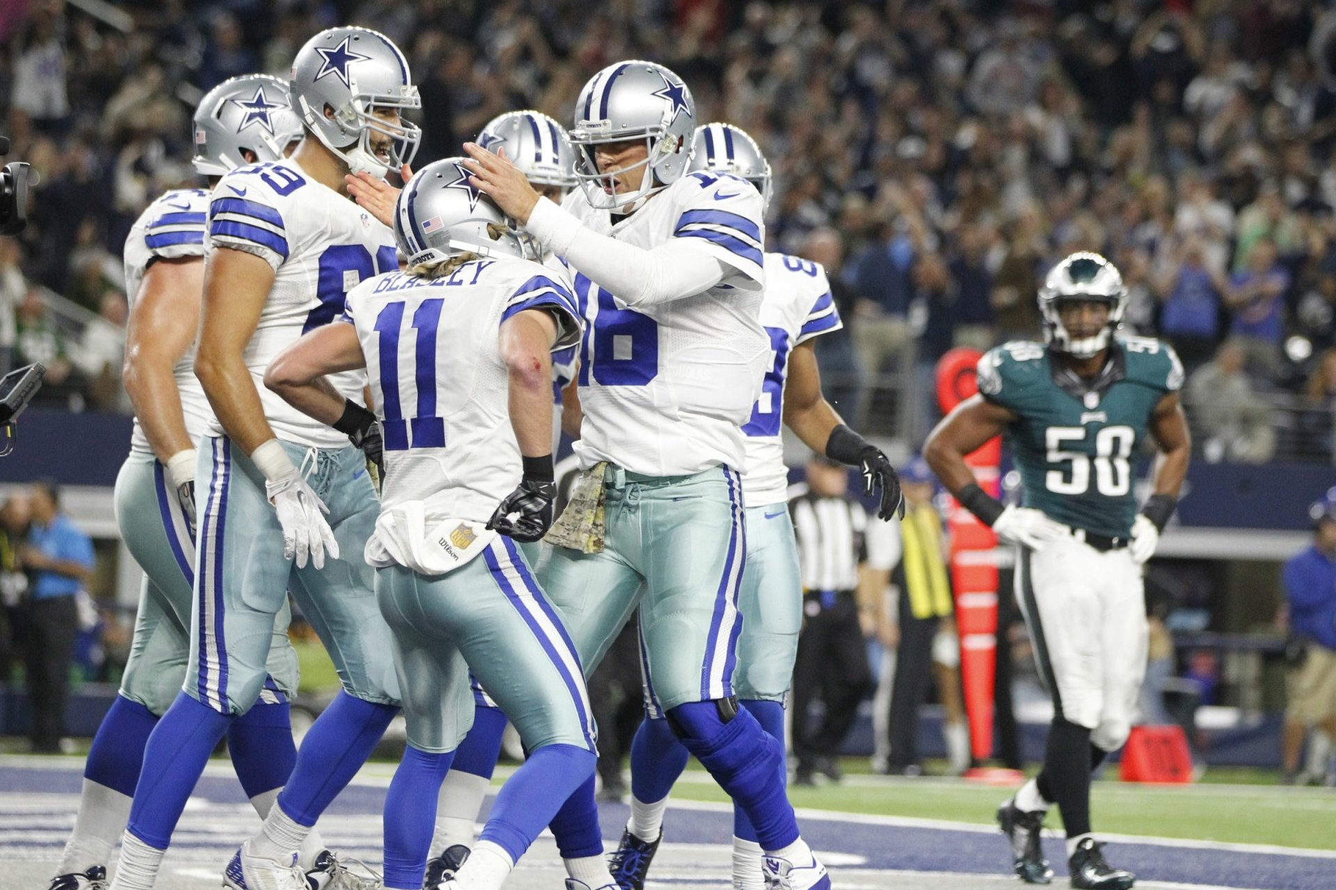 Dallas Cowboys players celebrating on the field under stadium lights — HD PC desktop wallpaper and background sports image.