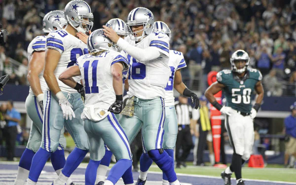 Dallas Cowboys players celebrating on the field under stadium lights — HD PC desktop wallpaper and background sports image.