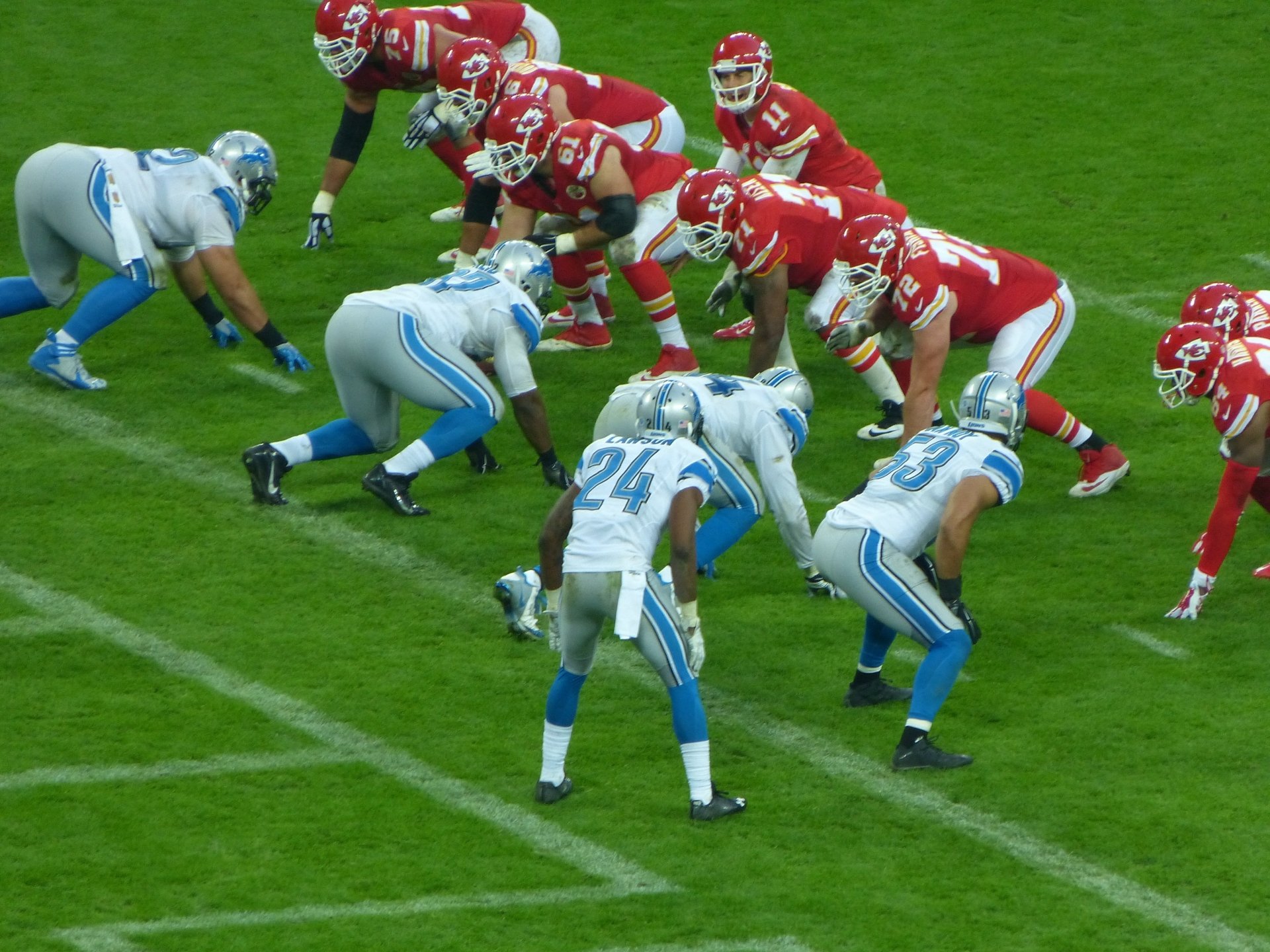 Kansas City Chiefs and blue-clad opponents lined up at the line of scrimmage on vivid green turf — 4K Ultra HD sports PC desktop wallpaper/background.