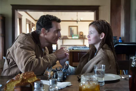 HD PC desktop wallpaper featuring Mackenzie Foy and Matthew McConaughey in a scene from the movie Interstellar, sitting at a dining table and holding hands.