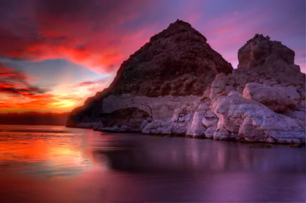 HD desktop wallpaper showcasing a glowing sunset sky with vibrant clouds above a serene lake and rocky formations, highlighting nature's tranquil beauty.