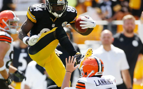 A dynamic action shot featuring a Pittsburgh Steelers player leaping over a Cleveland Browns opponent during a game, showcasing high-intensity sports excitement.