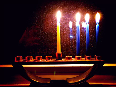 Hanukkah menorah with glowing candles reflected on a dark background — 2K Quad HD PC desktop wallpaper and background, warm candlelight ambiance.