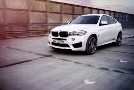 White BMW X6 driving on an urban road, captured in high-definition for a desktop wallpaper featuring sleek vehicle design and motion blur effects.