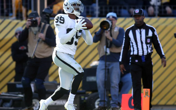 HD sports PC desktop wallpaper: Las Vegas Raiders player in white uniform catching a pass on the field, referees and photographers visible in the stadium background.