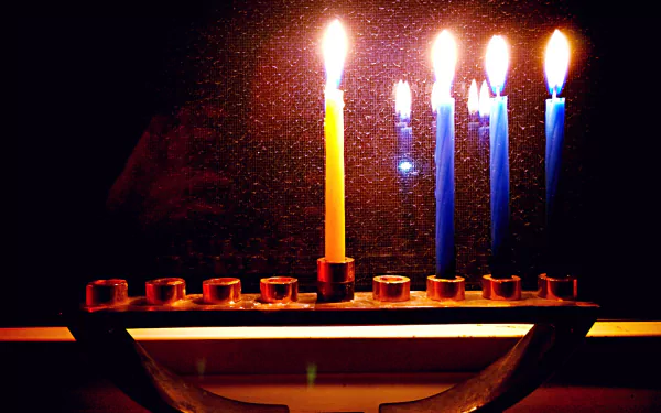 Hanukkah menorah with glowing candles reflected on a dark background — 2K Quad HD PC desktop wallpaper and background, warm candlelight ambiance.