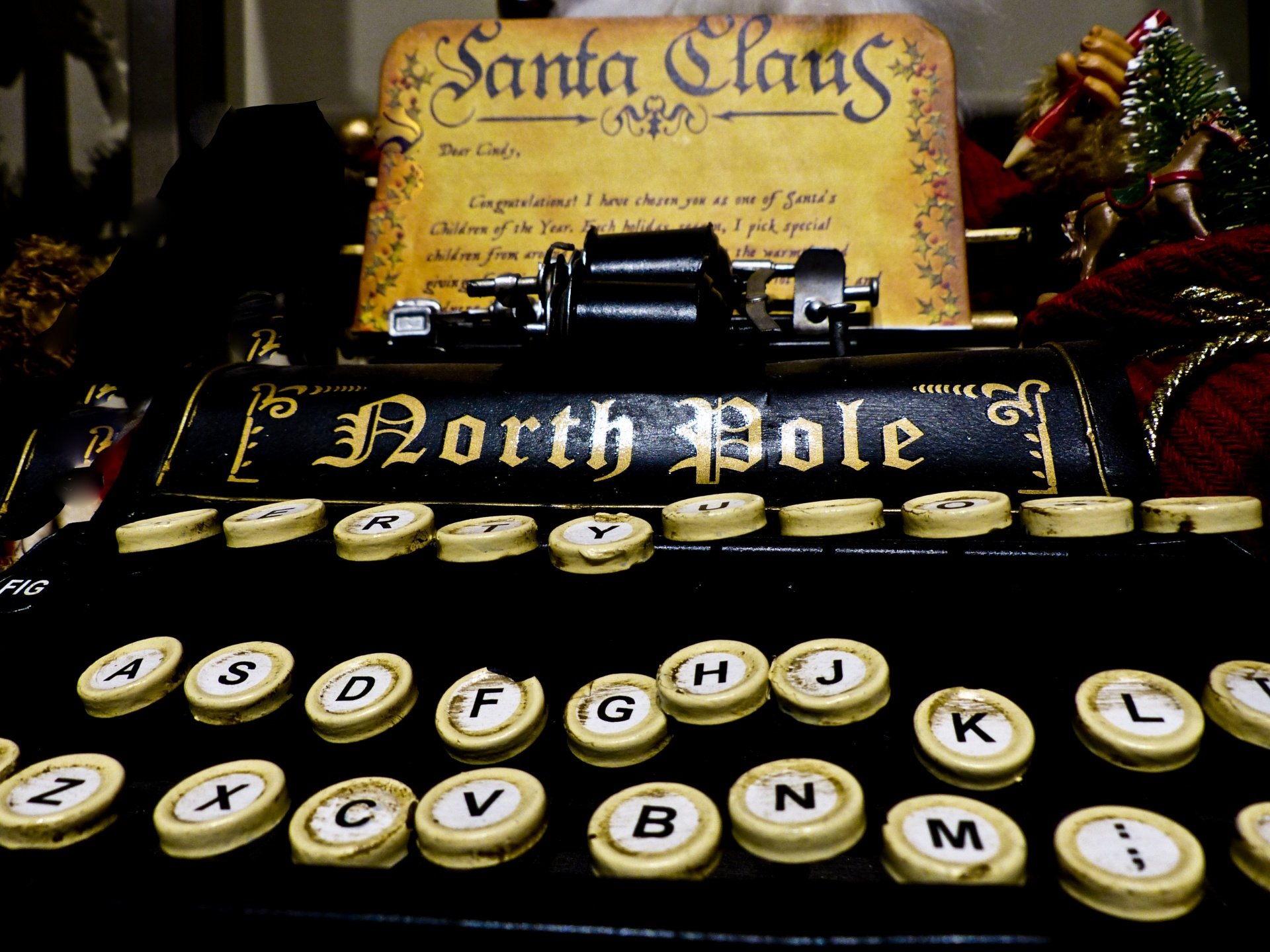 Close-up of a vintage typewriter with North Pole on the roller, surrounded by holiday and Christmas decorations, featured as an HD PC desktop wallpaper.