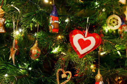 HD PC desktop wallpaper background: close-up of a decorated Christmas tree with glowing lights, a red heart ornament and assorted gold and glass ornaments for the holiday.