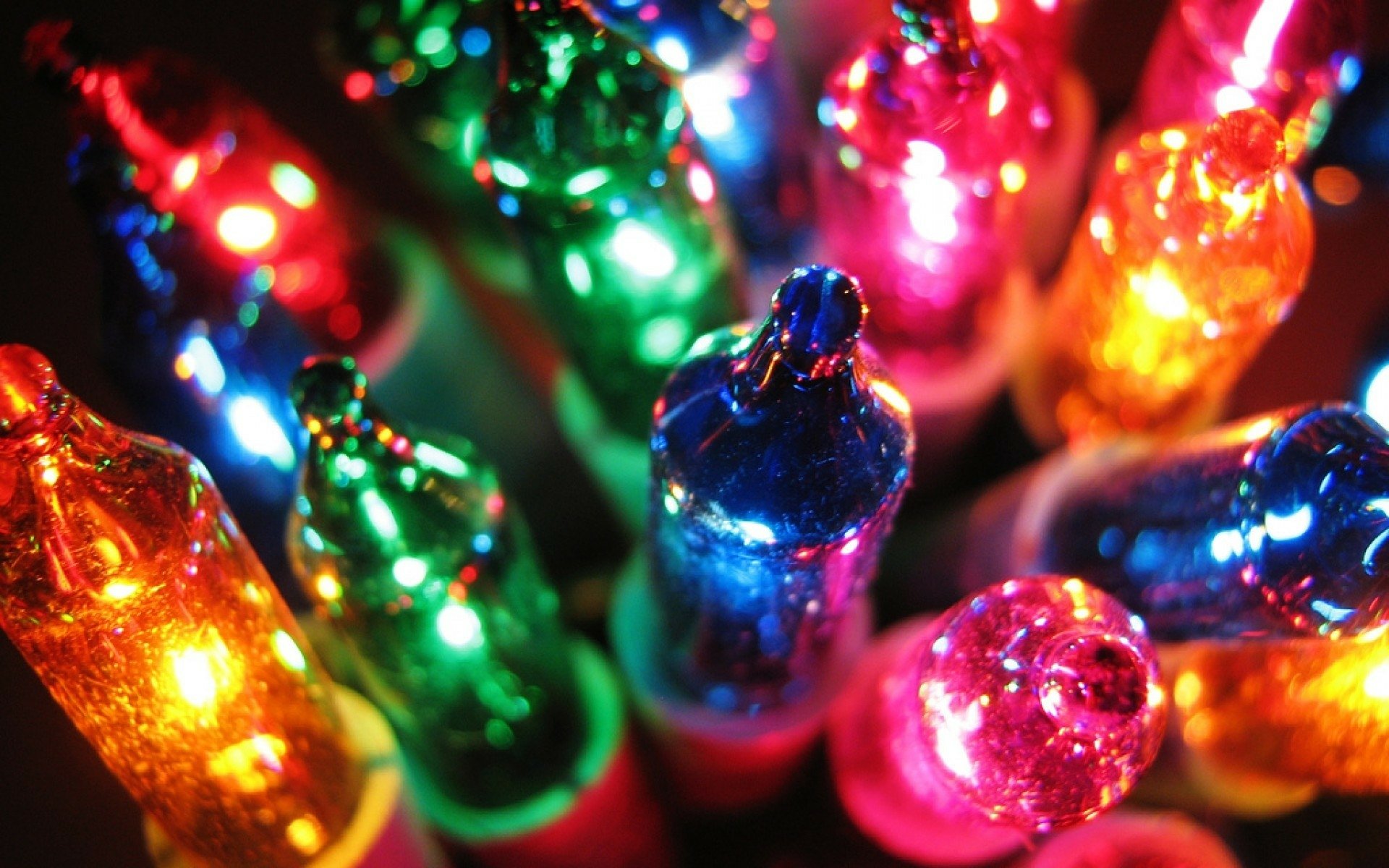 Close-up of colorful glowing Christmas lights in red, green, blue and yellow, festive holiday HD PC desktop wallpaper and background.