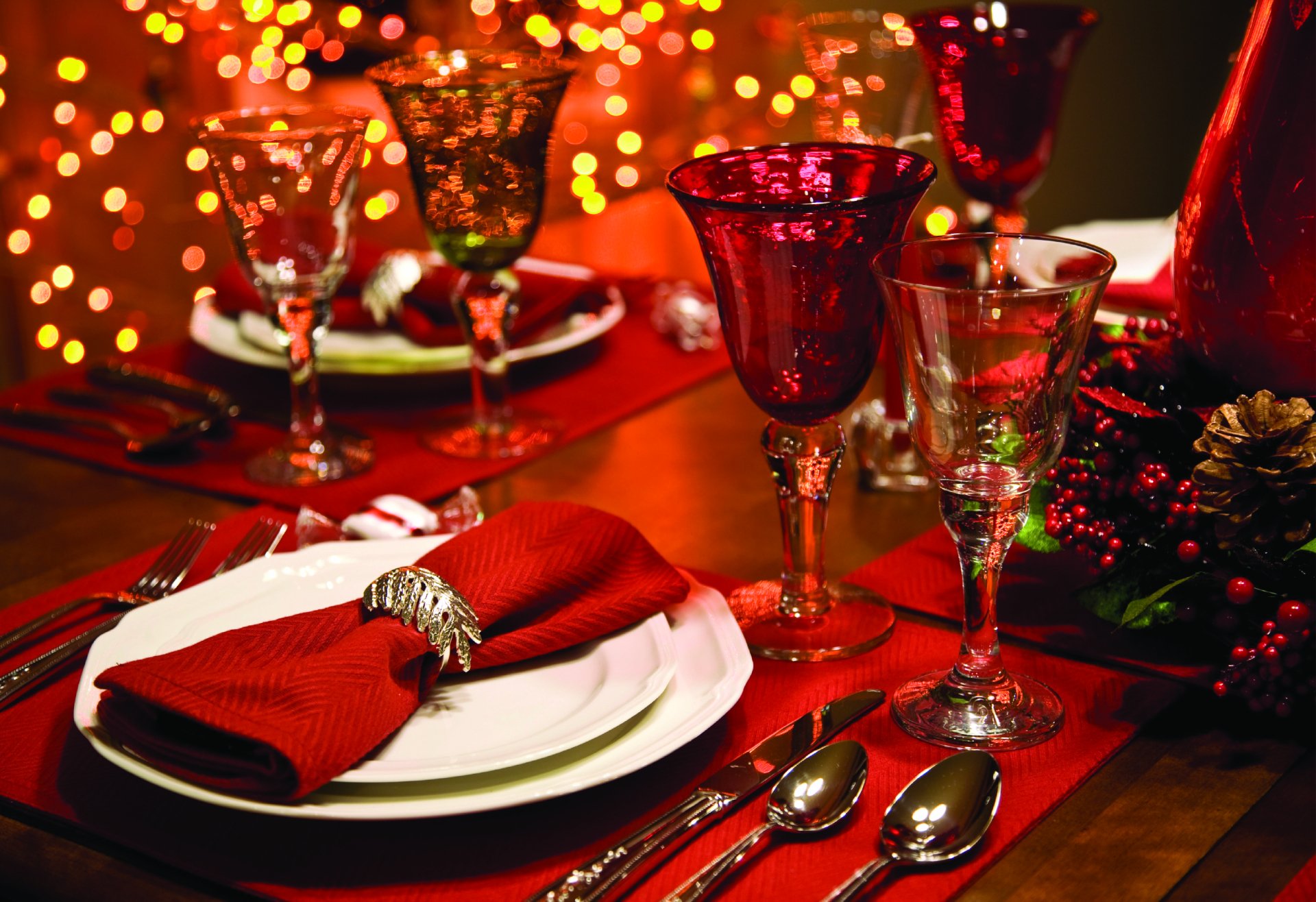 Festive holiday table setting with red glassware, a folded red napkin, and sparkling Christmas bokeh lights in an 8K Ultra HD desktop wallpaper scene.