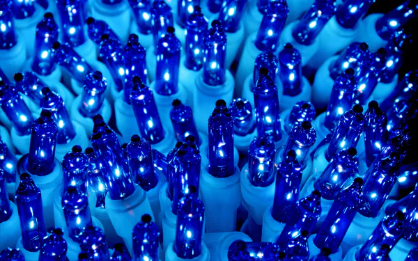 Close-up of vibrant blue Christmas holiday lights glowing in 4K Ultra HD, creating a festive and bright PC desktop wallpaper background.