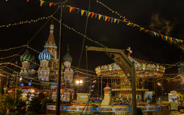 Night 4K Ultra HD PC wallpaper of Saint Basil's Cathedral in Moscow beside man-made amusement park rides, colorful lights, strings of bunting and an illuminated carousel.