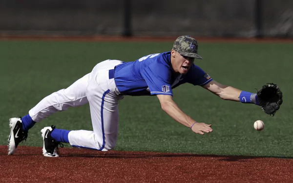 A baseball player in a blue uniform dives to catch a ball on a turf field, captured in this HD PC desktop wallpaper showcasing intense sports action.