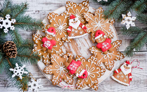 Holiday-themed gingerbread cookies shaped like snowflakes, reindeer, and Santa Claus arranged in a wreath on a rustic wooden background with pine branches and snowflake decorations.