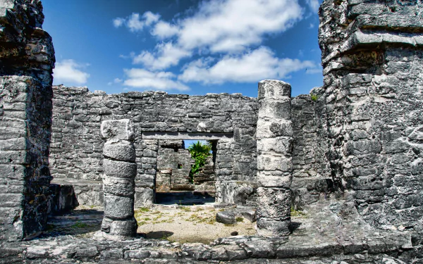 4K Ultra HD PC desktop wallpaper of man-made stone ruins at Tulum, Mexico — weathered columns and doorways framing blue sky and coastal vegetation.