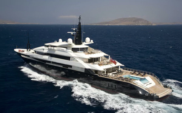 HD PC desktop wallpaper/background of a luxury yacht (vehicle) cutting through deep-blue sea, wake trailing toward a distant island.