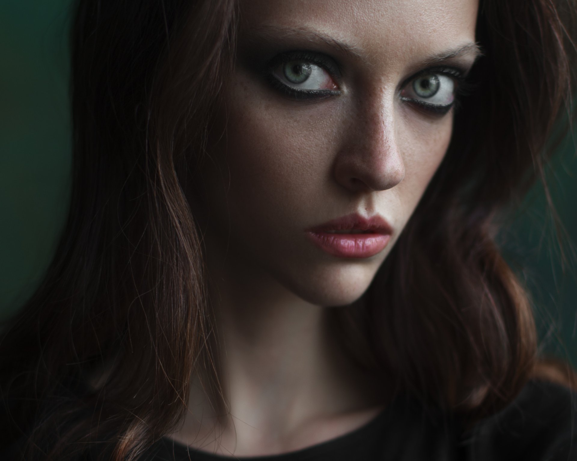 HD desktop wallpaper featuring a close-up portrait of a brunette woman with striking green eyes and a serious expression.