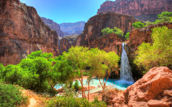 A stunning HDR landscape featuring a waterfall cascading down a cliff, framed by vibrant greenery and rocky terrain, showcasing the beauty of nature in 4K Ultra HD.