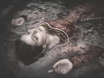 HD desktop wallpaper of a brunette model lying calmly in water, exuding a serene and contemplative mood.