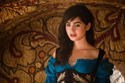 Lily Collins, a brunette English actress, stars in Mirror Mirror. The image captures her in a vibrant blue dress, set against a richly patterned background.