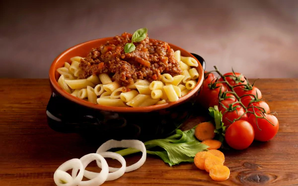 HD desktop wallpaper featuring a bowl of pasta topped with tomato meat sauce, surrounded by fresh tomatoes, basil, onion rings, and carrot slices on a wooden surface.