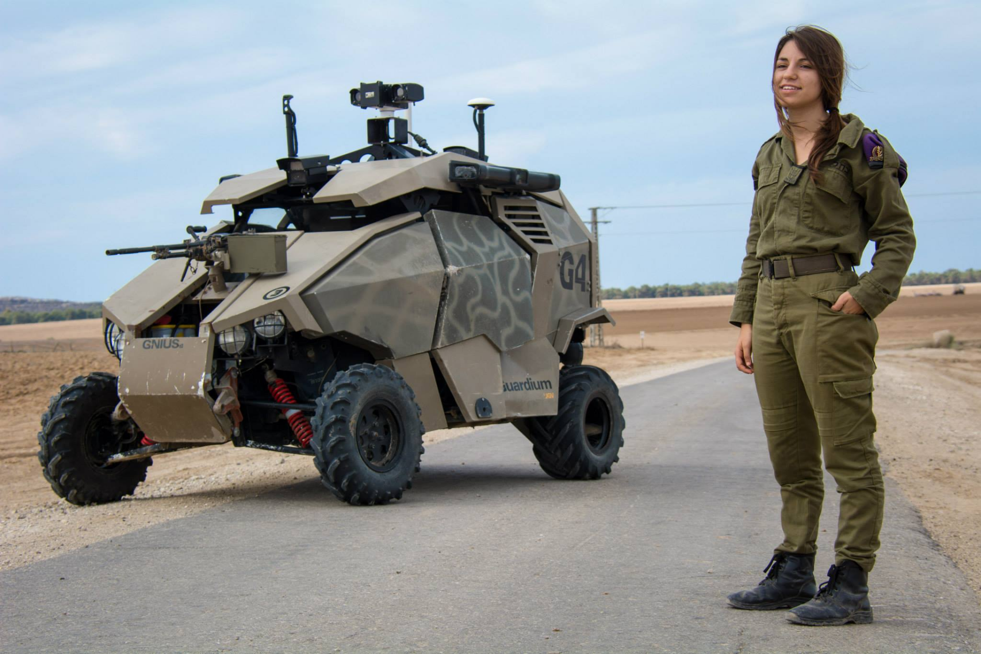 A soldier stands beside a futuristic military vehicle on a barren road, showcasing strength and innovation in a high-definition PC desktop wallpaper.