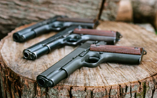 HD wallpaper featuring a collection of Colt 1911 pistols arranged on a wooden stump, showcasing their iconic design and craftsmanship against a natural backdrop.