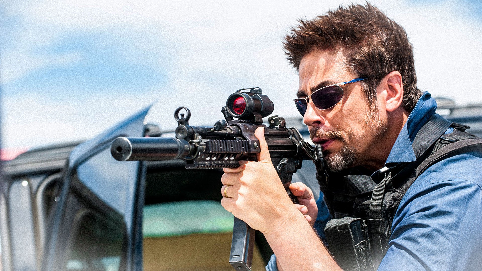 HD PC desktop wallpaper/background from the movie Sicario: armed man in sunglasses and tactical gear aims a rifle from an open vehicle against a bright sky.
