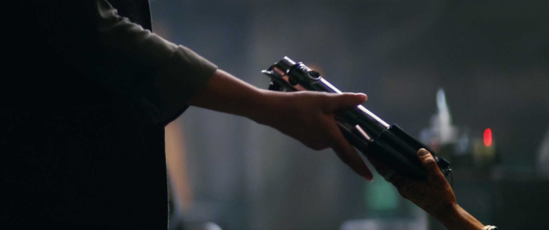 Close-up of two hands exchanging a lightsaber hilt in a cinematic still from the movie Star Wars: Episode VII — 2K Quad HD PC desktop wallpaper.