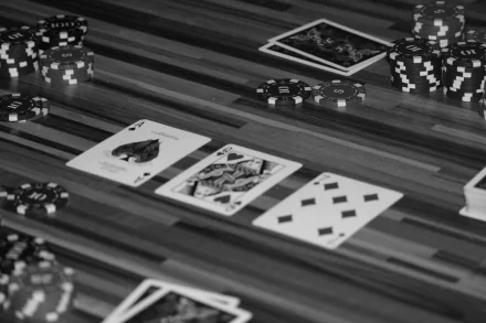 Black and white 4K Ultra HD desktop wallpaper featuring a close-up of poker chips and playing cards arranged on a wooden surface, highlighting a man-made gaming scene.