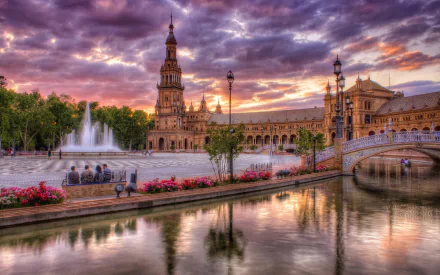 A stunning HDR image showcasing the Royal Alcázar Palace in Seville, Spain, reflecting in the water at sunset, surrounded by vibrant flowers and beautiful architecture.
