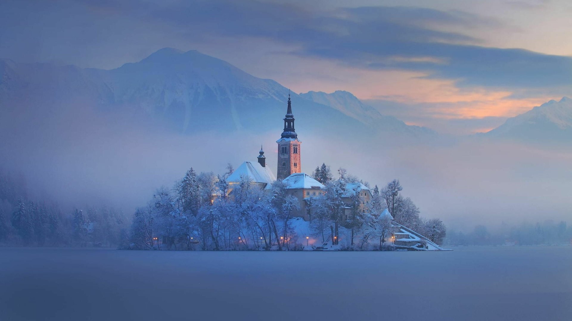 HD desktop wallpaper of a serene church on a snowy island at dawn, surrounded by mist and soft pastel skies, creating a peaceful religious atmosphere.