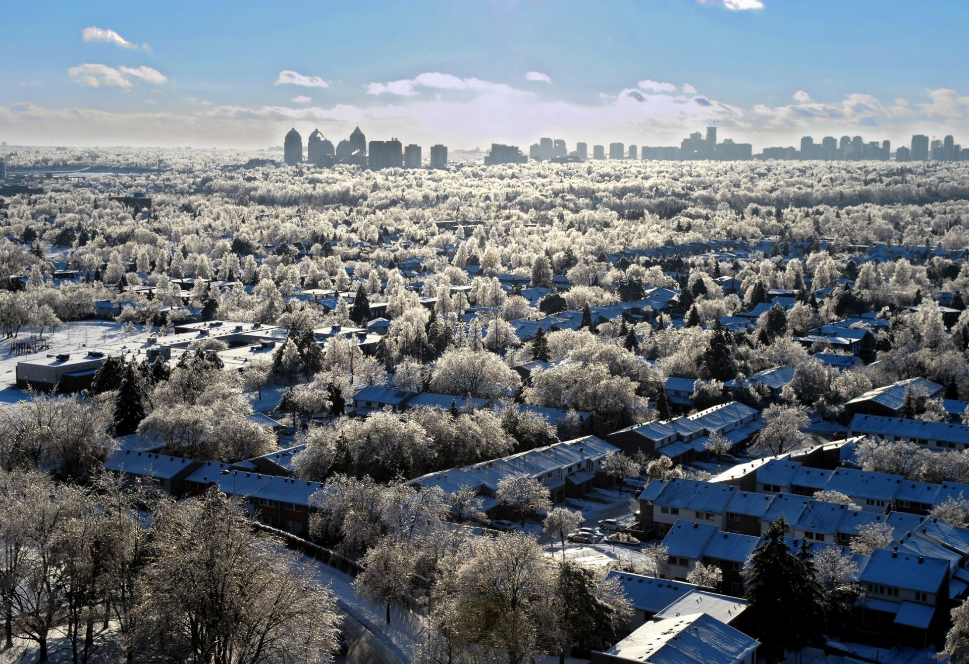 HD desktop wallpaper showcasing a man-made Toronto skyline in the distance above a sprawling snow-covered residential neighborhood.