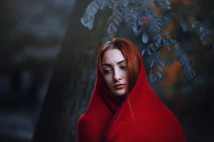 HD PC desktop wallpaper featuring a redhead woman wrapped in a red shawl, set against a moody background with soft bokeh lighting and dark foliage.