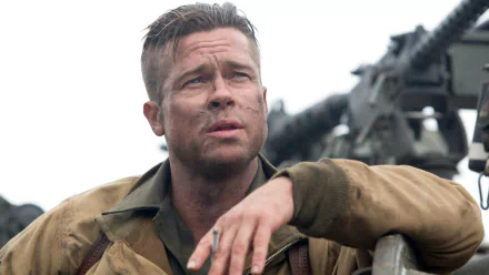 A dramatic HD desktop wallpaper featuring Brad Pitt in the movie Fury, portraying a weary soldier with a rugged look, set against a backdrop of military equipment.