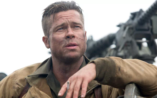 A dramatic HD desktop wallpaper featuring Brad Pitt in the movie Fury, portraying a weary soldier with a rugged look, set against a backdrop of military equipment.