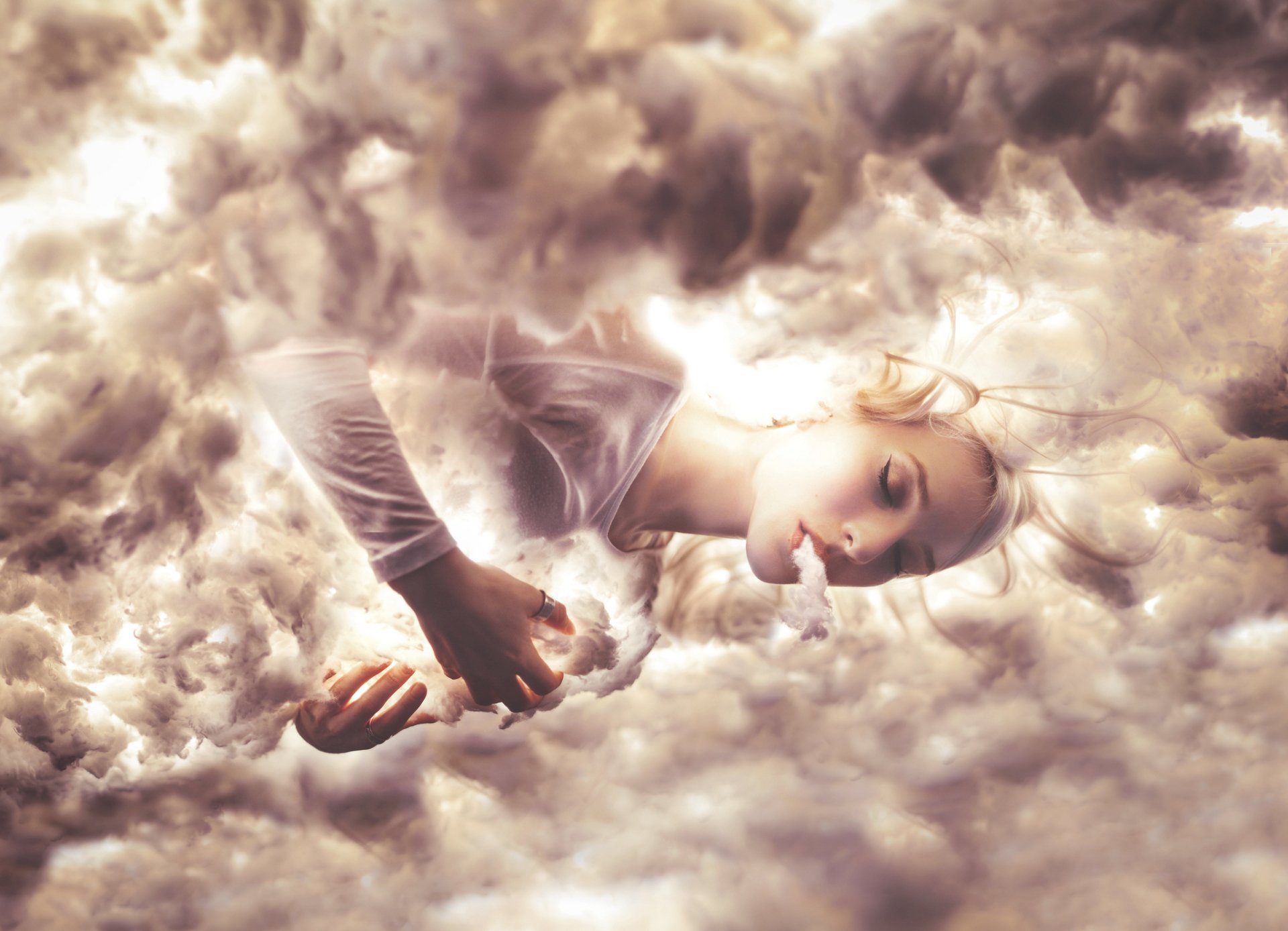 A blonde figure lies enveloped in swirling smoke, captured through stunning photography manipulation, creating an ethereal HD desktop wallpaper.