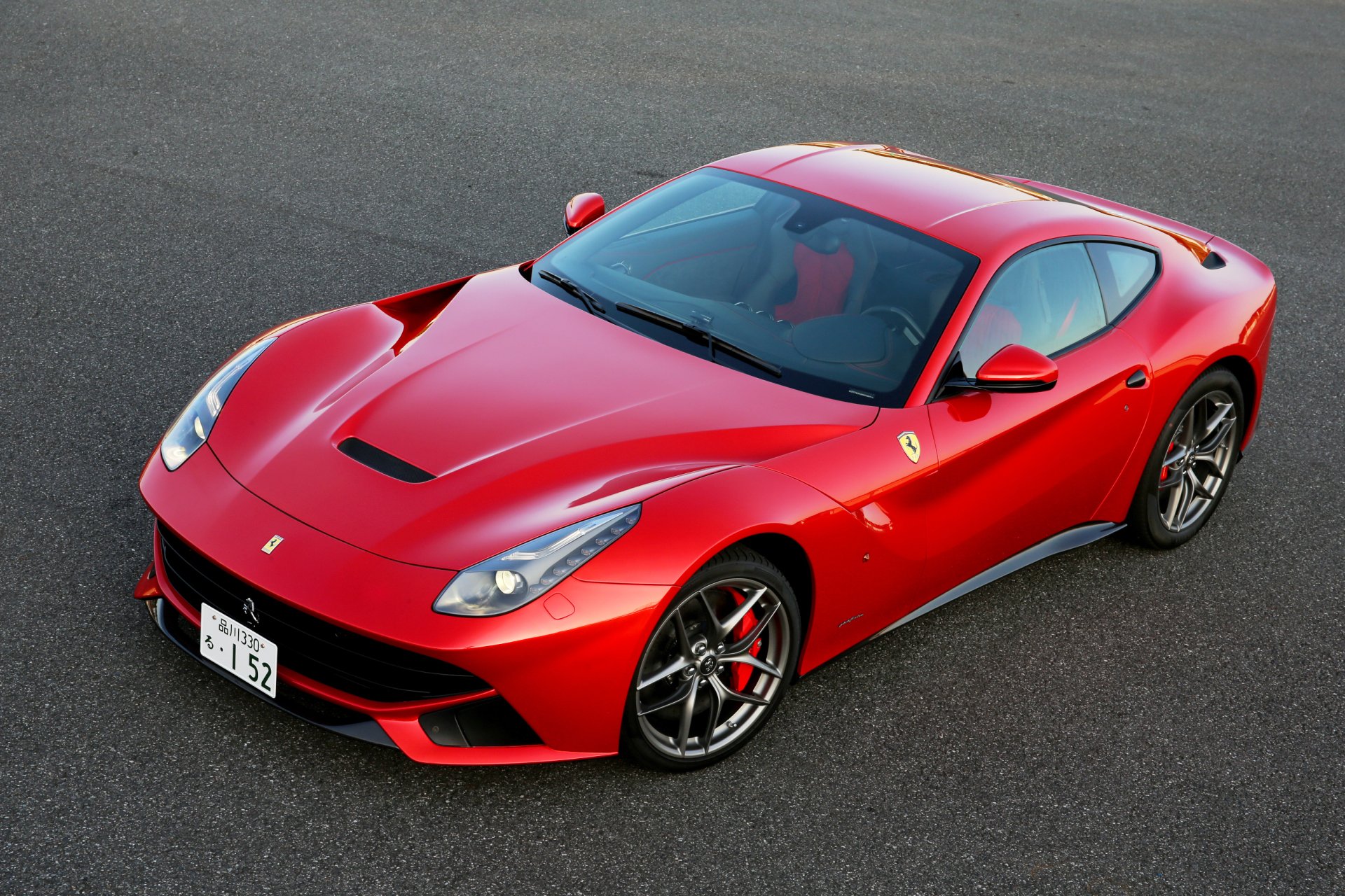 HD desktop wallpaper featuring a red Ferrari F12berlinetta supercar parked on asphalt, showcasing its sleek design and sporty elegance.