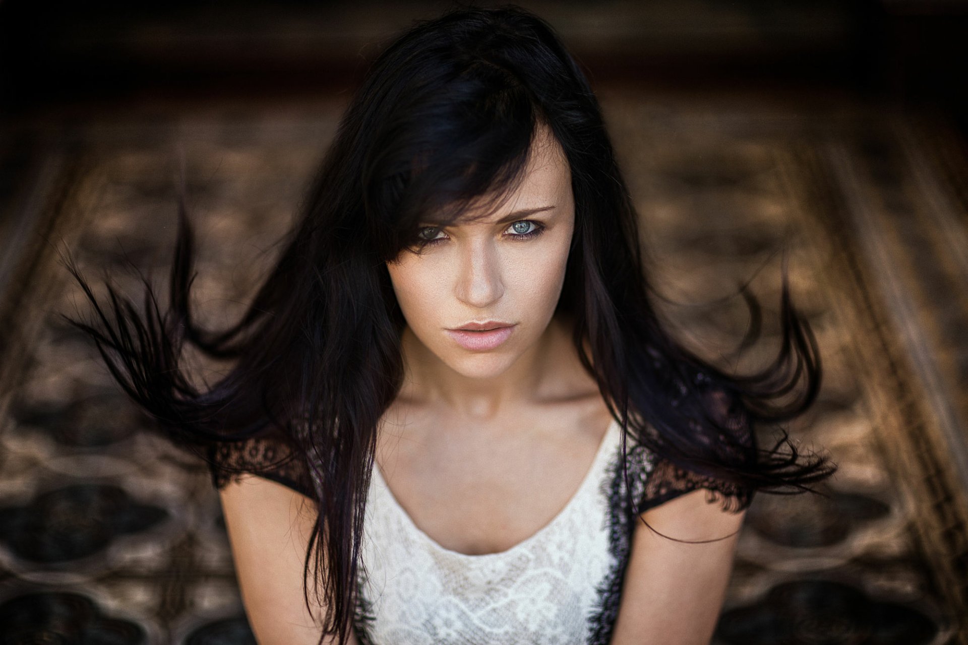 HD desktop wallpaper of a brunette woman with striking blue eyes against a soft bokeh background, capturing a captivating and stylish model portrait.