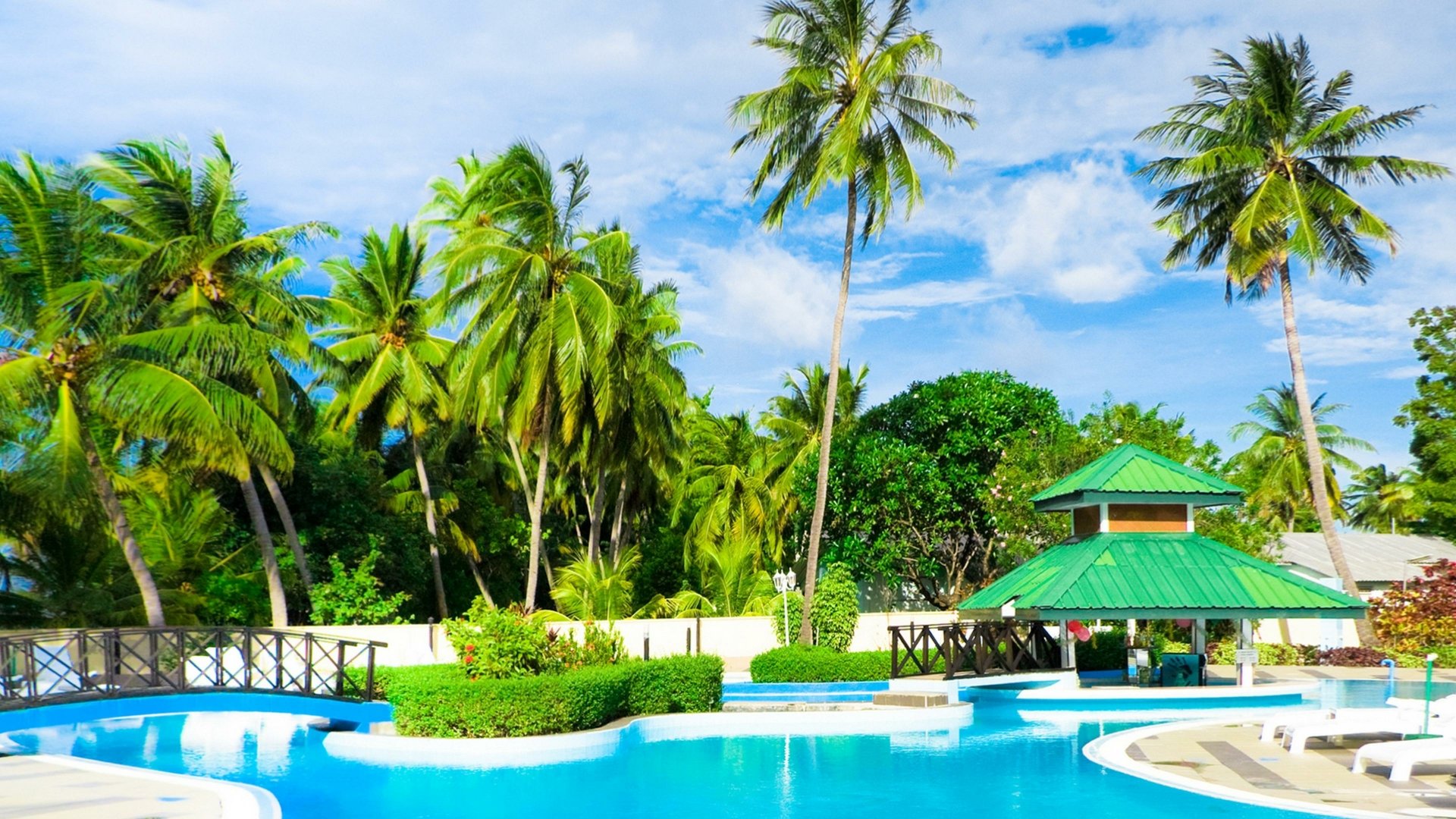 4K Ultra HD wallpaper of a tropical resort featuring a clear blue pool, palm trees, and a green-roofed gazebo under a bright sky.