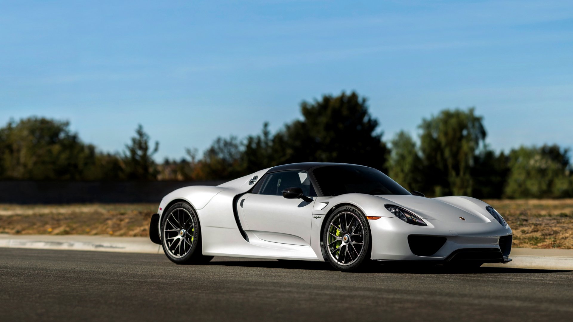 White Porsche 918 Spyder supercar parked on a sunlit road, side profile; 2K Quad HD PC desktop wallpaper/background of the vehicle.